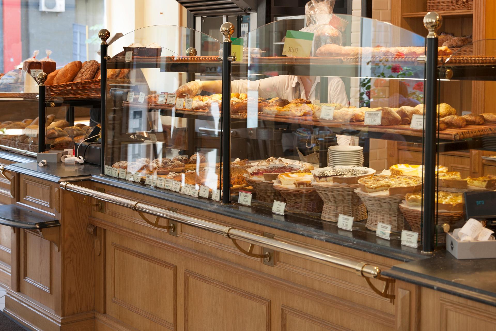 A variety of freshly baked goods displayed in a bakery case with a staff member in the background.